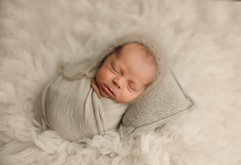 newborn swaddled in cream on pillow, Dallas newborn photographer