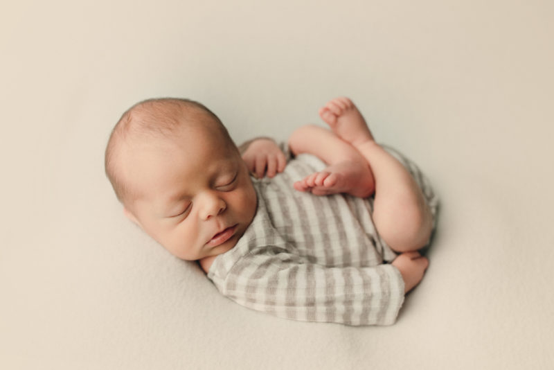 newborn in striped onesie on white blanket, dallas newborn photographer