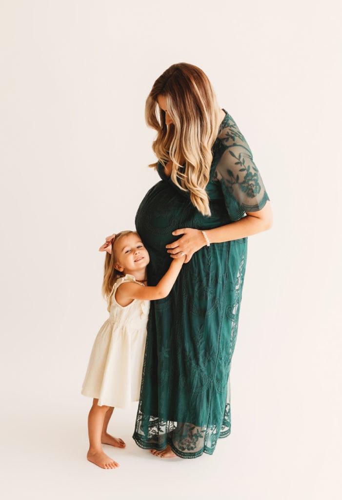 maternity photographer, toddler daughter reaches to feel mom's pregnant belly