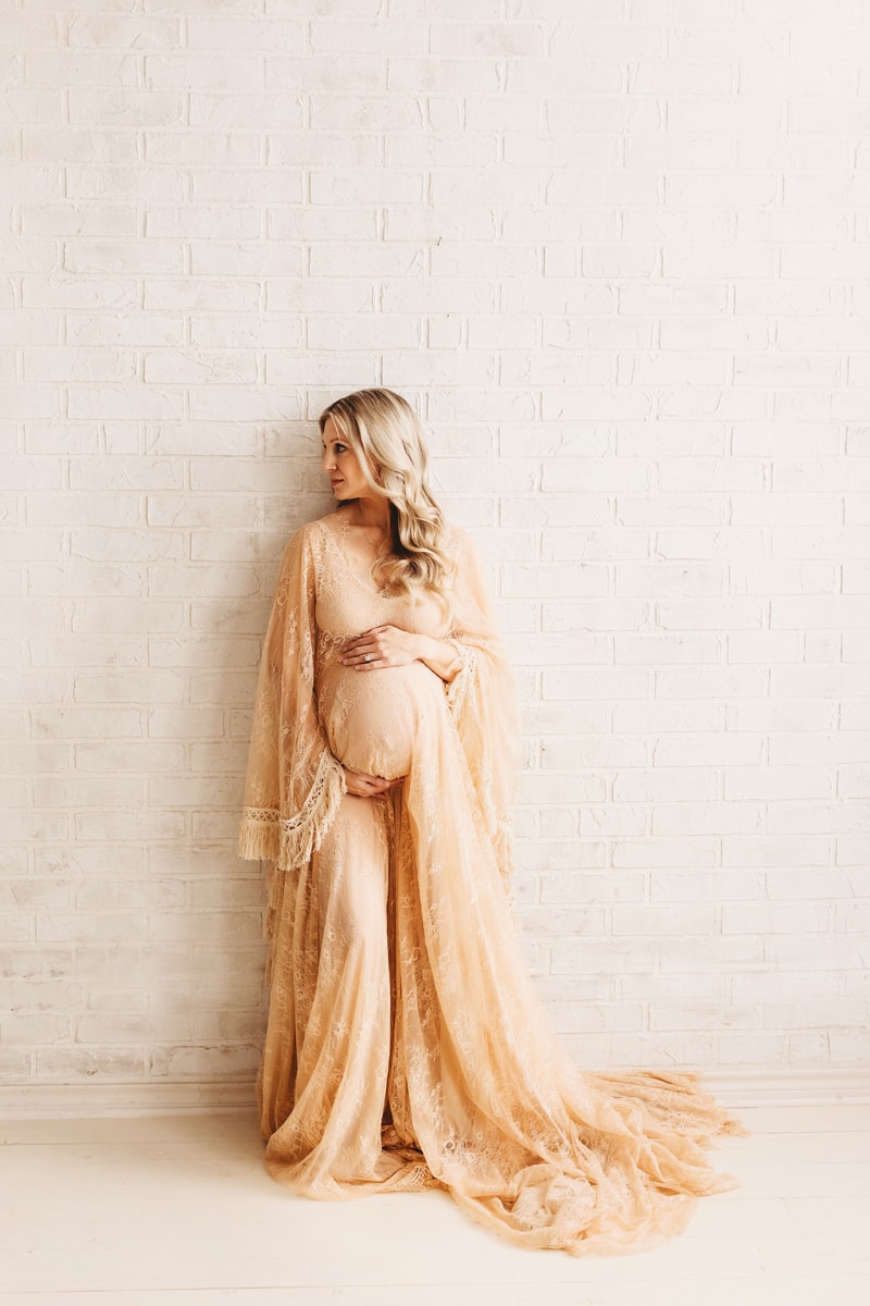 Beautiful mom to be posed on brick wall in Frisco, Texas maternity photo studio.