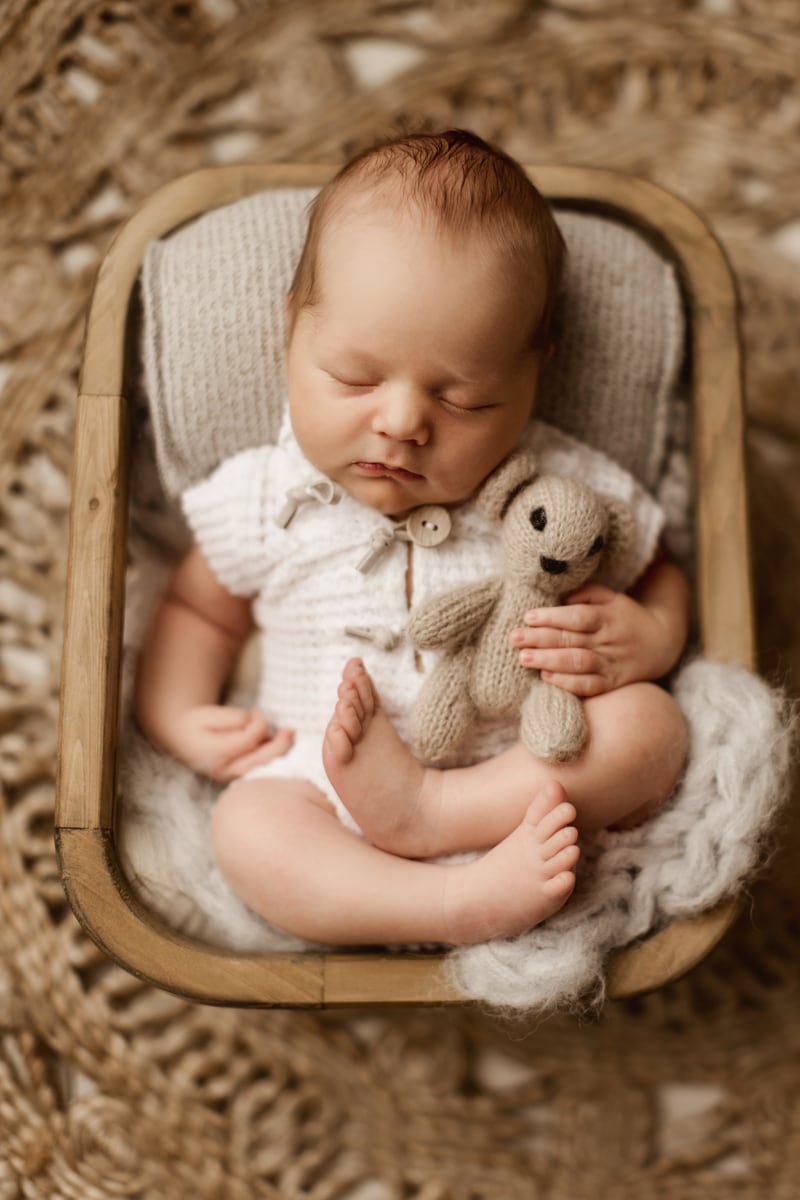 Newborn baby boy holding a tiny bear in Frisco newborn photography session.