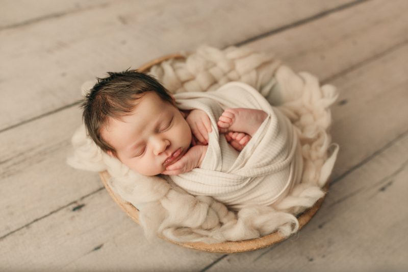 baby swaddled neutral fur in bowl
