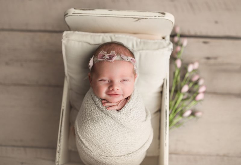 newborn girl in baby bed smiling, frisco newborn photos