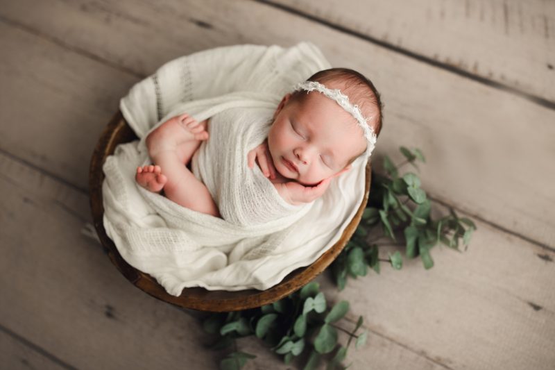newborn swaddled in wooden bowl with greenery, frisco newborn photos