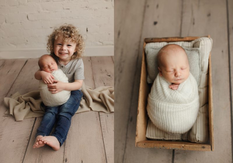 big brother holding newborn baby and baby in wooden crate sleeping