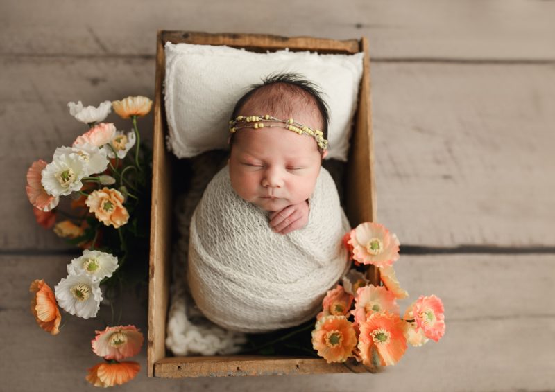newborn swaddled in white in wooden box with orange flowers, mckinney newborn photo session baby ada 