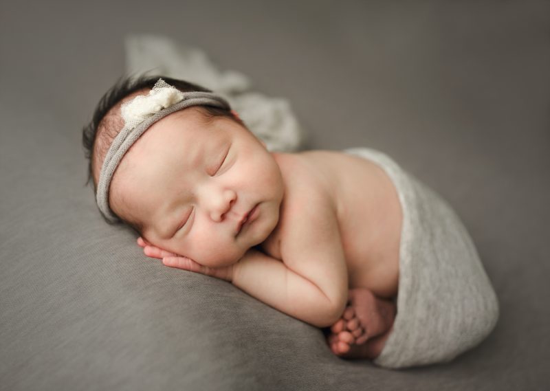 newborn swaddled in gray on gray blanket