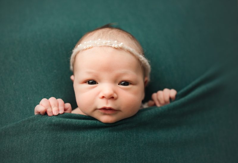 newborn girl peeking over green blanket, dallas newborn photo session baby mavis