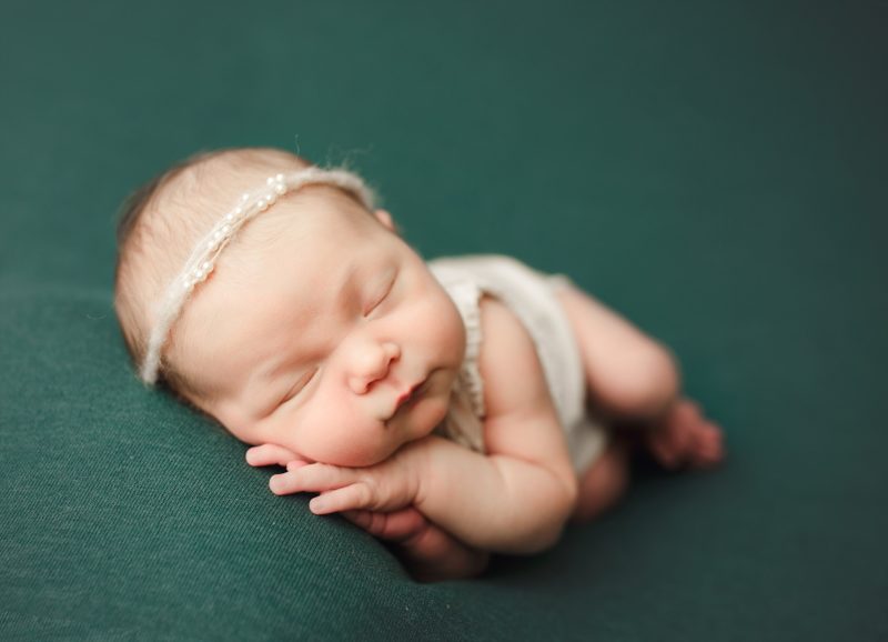 newborn sleeping on arms and hands on green blanket, dallas newborn photo session baby mavis