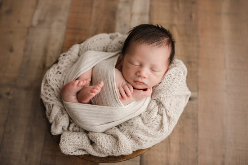 newborn sleeping swaddled in cream on cream knit blanket wood floor, baby beckham newborn session frisco texas