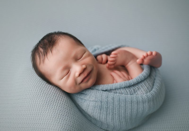 newborn smile swaddled in blue sleeping on blue blanket, baby beckham newborn session frisco texas
