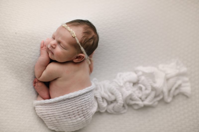 newborn laying on belly on white blanket with swaddle, dallas newborn photography session baby giuliana