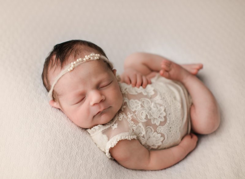 newborn swaddled in cream outfit