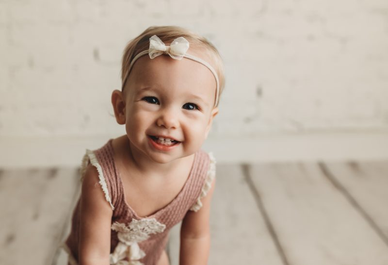 baby girl smiling white brick backdrop, mckinney baby photo session baby charlie