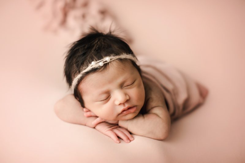 newborn girl laying on arms on pink blanket_dallas baby photo session baby leia