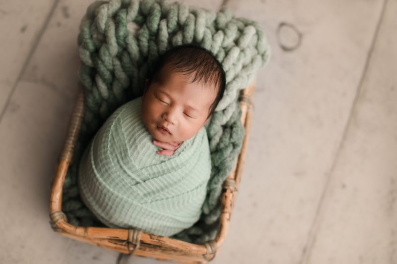 newborn boy swaddled in green in crate_mckinney baby photo session baby alex