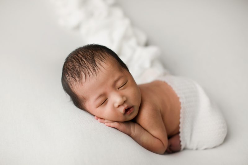 newborn boy laying on hands on white blanket_mckinney baby photo session baby alex