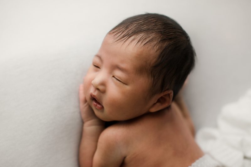newborn boy laying on hands with white blanket_mckinney baby photo session baby alex