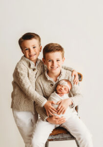 two brothers holding their sister during a newborn photography session