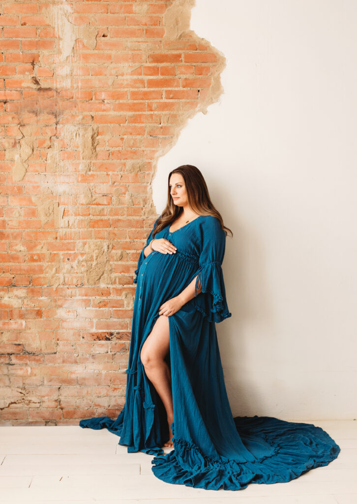new mother in blue dress on brick wall
